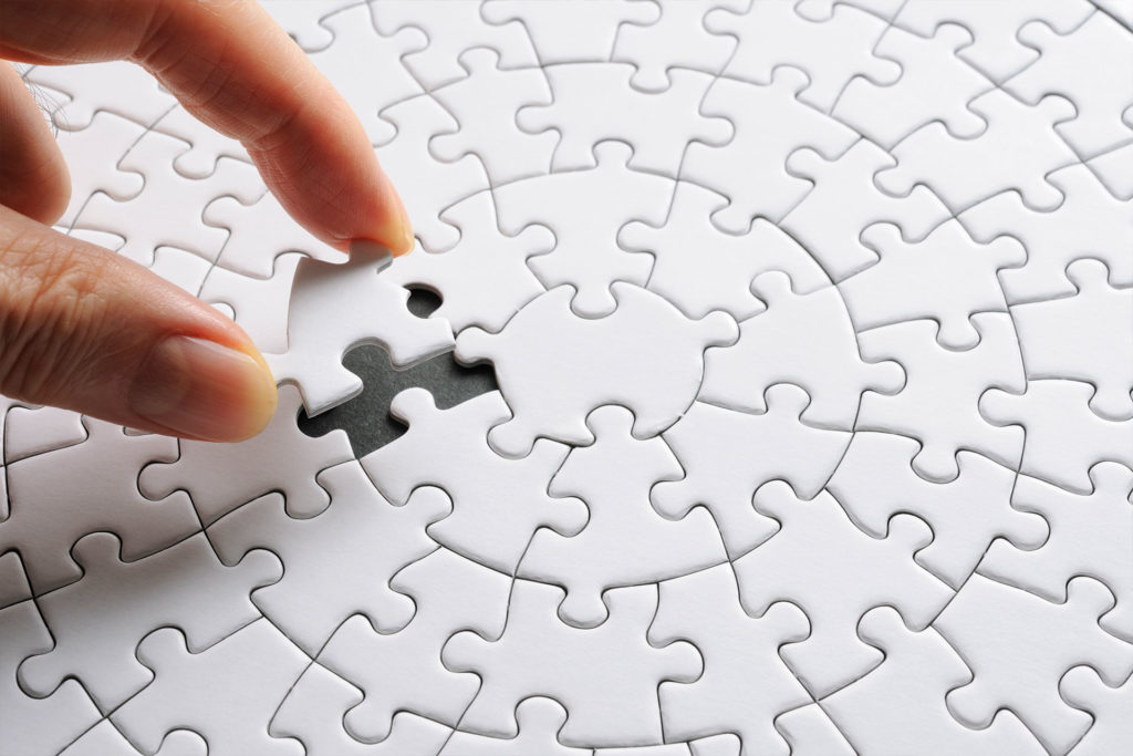 symbolic image for operator models white puzzle in which a hand inserts the last missing puzzle piece